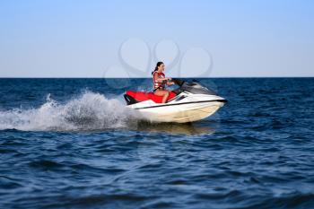 Young caucasian woman in life jacket on a wave runner