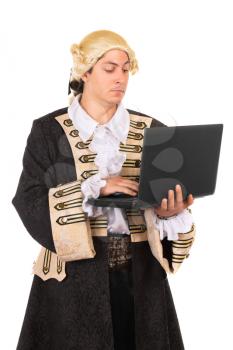 Funny young man wearing medieval costume and posing with a laptop. Isolated on white