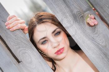Portrait of cute woman behind the wooden fence