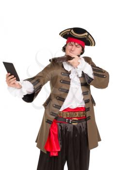 Portrait of young man in pirate costume aiming in the tablet. Isolated