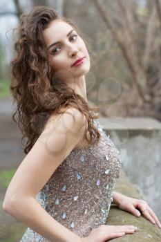 Beautiful young brunette with long curly hair wearing luxury grey dress