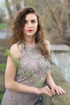 Attractive young lady wearing splendid grey dress with rhinestones