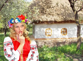 Beautiful girl in the Ukrainian national costume in garden near the house