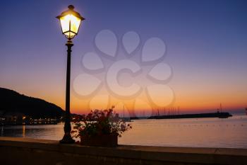 Lighted lantern on coast of the Tyrrhenian Sea on the sunset. Elba Island, Italy