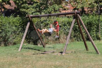 Grazzano Visconti, Italy - August 07, 2016: Children ride on wooden swing
