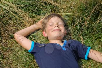 Handsome boy lying on meadow grass