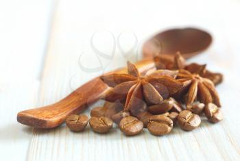 Coffee grains with anise star and wooden old-style spoon on vintage wooden table food ingredients background. Selective focus. Coffee drink aroma ingredients.