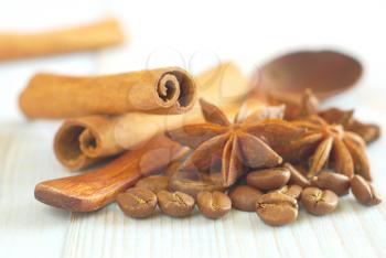 Coffee grains with anise star, wooden old-style spoon and cinnamon sticks on vintage wooden table food ingredients background. Selective focus. Cappucino ingredients food backdrop.