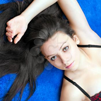 portrait of a young girl lying on  blue background