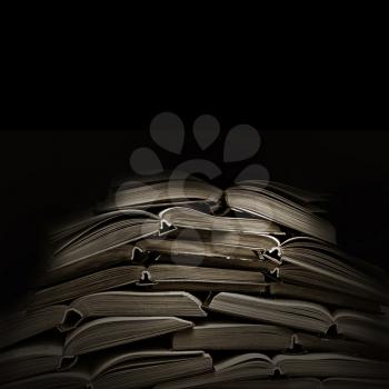 stack of open old books in black background