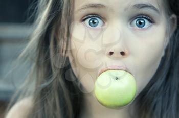 Royalty Free Photo of a Surprised Young Girl Eating an Apple