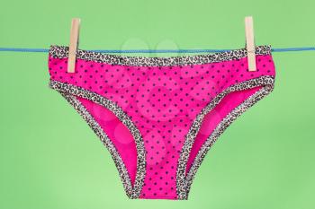 Pink panties hung on the clothes line.Isolated on green background