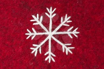 close-up of red felt with embroidered white snowflake