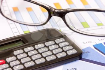 Financial data analyzing. Close-up photo of diagrams, calculator and glasses 