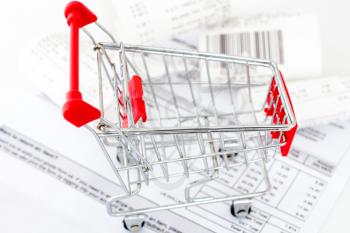 Consumerism concept. Shopping cart with receipts on white background 