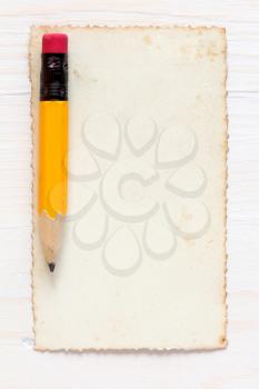 Yellow pencil with old paper on wood