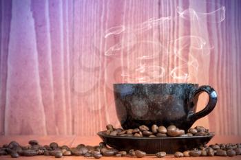 Small cup of black coffee on a wooden background with coffee beans