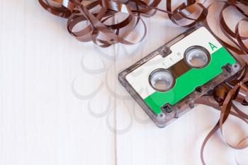 Audio cassette with pulled out tape on the wooden background with copy space