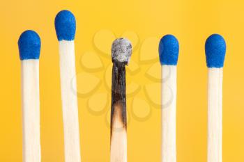 Four matches and one burnt on yellow background