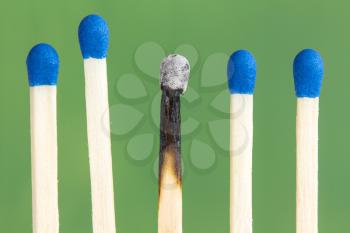 Row of match sticks with blue heads, over a green background