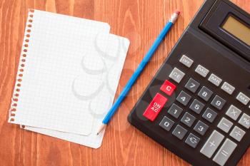 Paper sheets and calculator on wooden background