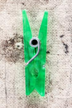 Close up view of  green plastic clothespin  on dirty background