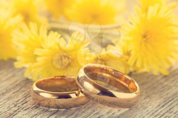 Wedding rings with yellow flowers on wooden background