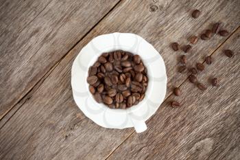 Coffee cup with roasted coffee beans on wooden background. Top view image.