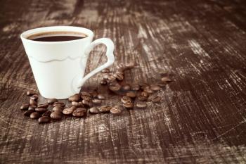 Coffee cup with roasted coffee beans on wooden background.