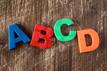  ABCD spelling from plastic letters on wooden background