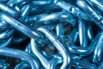 Background of galvanized steel chain links, in blue tone. Shallow DOF.