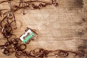   Audio cassette with pulled out tape on wooden background. Copy-space.