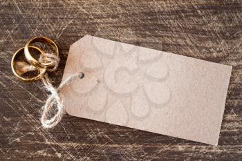 Wedding rings with blank tag on the wooden background