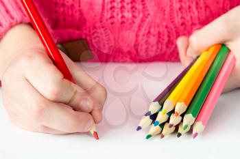 Child draws with colored pencils on paper