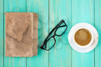 Old book with glasses and coffee cup on wooden background