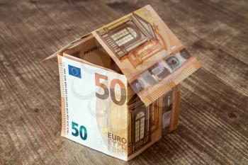 House made of fifty Euro banknotes on a wooden background