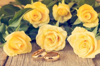 Wedding rings with yellow roses on background