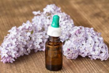 Essential aroma oil with lilac on wooden background