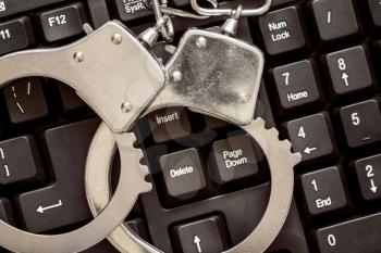 Online crime concept with handcuffs on computer keyboard