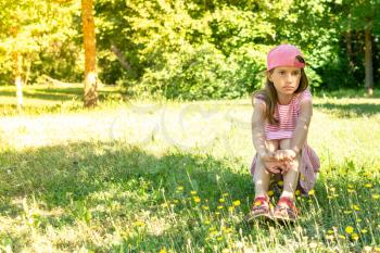 Dreamy girl child sitting on the grass in sunny spring meadow