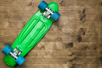 Overturned green skateboard lying on wooden background