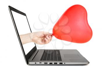 Hand reaches out of an Laptop with a heart shaped balloon. Internet dating concept