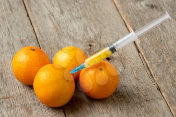 Syringe and mandarins. Concept for genetically modified food and cosmetic medicine
