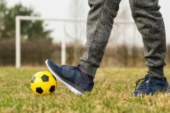 Feet of player with ball on a spring grass