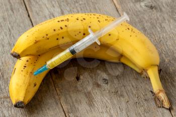 Syringe and banana bunch. Concept for genetically modified food and cosmetic medicine