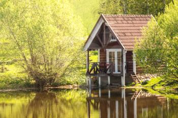 Small wooden house near the pond, sunny summer day