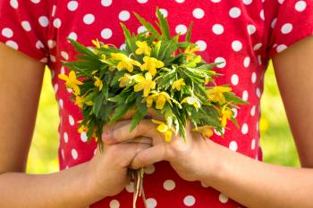 Girl holds small bouquet of wildflowers. Girl picking fresh flowers for mother's day