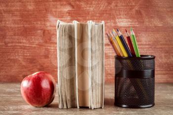 Books,apple and pencil cup on wooden background