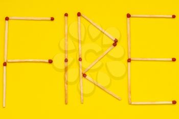 Word FIRE made with matches on yellow background
