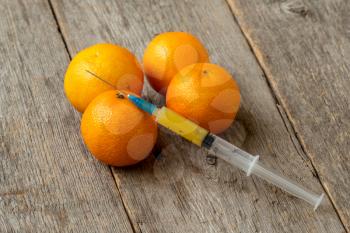 Syringe and tangerines. Concept for genetically modified food and cosmetic medicine